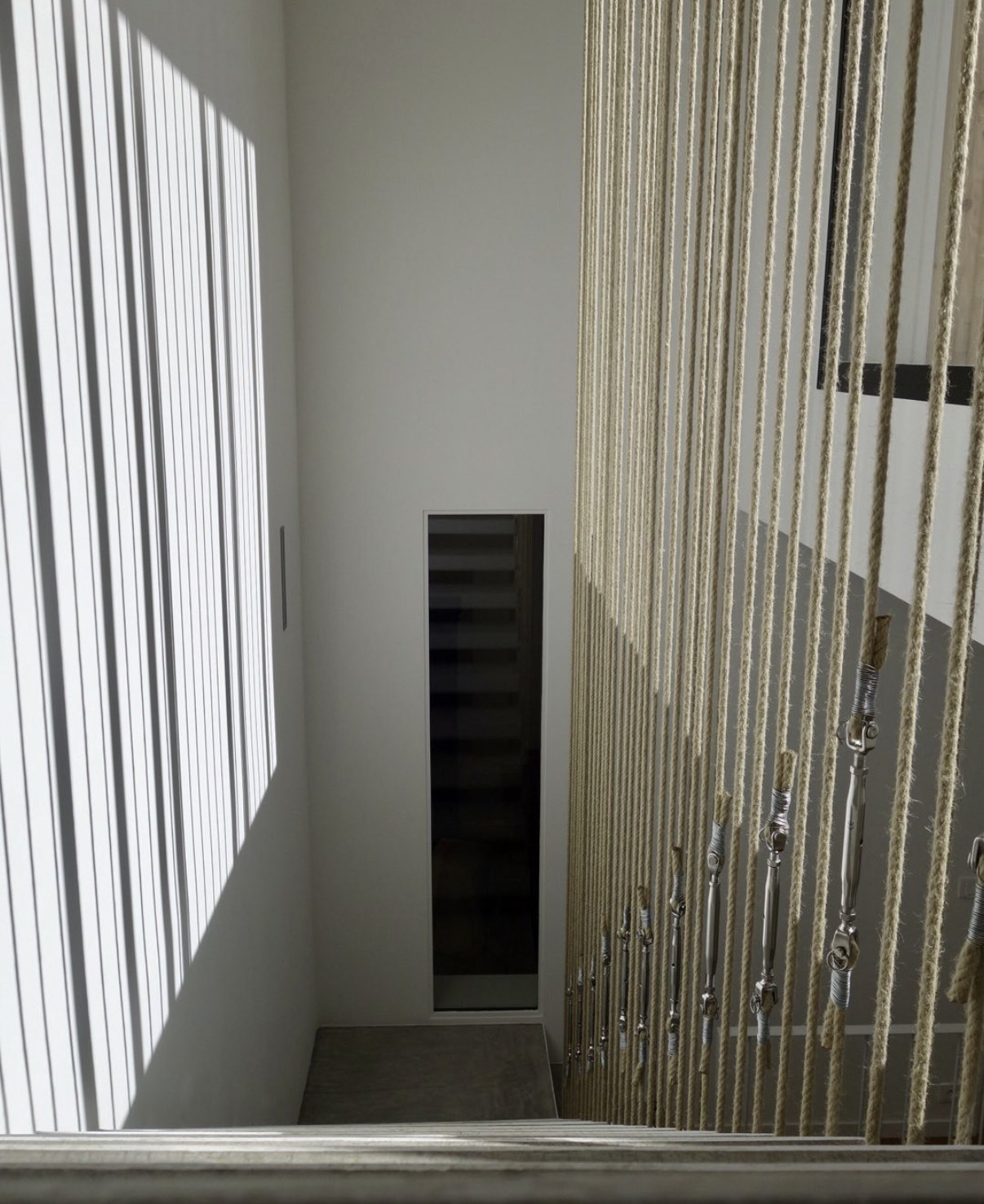 Maison Vito à Paris 20e — garde-corps en cordes tendues baigné de lumière